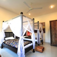 Slaapkamer met twee ruime éénpersoonsbedden voorzien van klamboe.