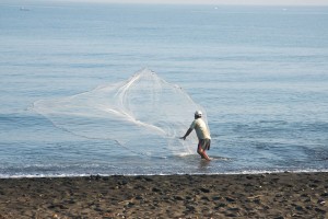 Man vist met net op strand van Bali.